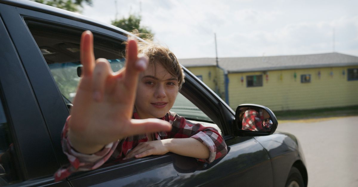 A girl hangs out a car window in CODA