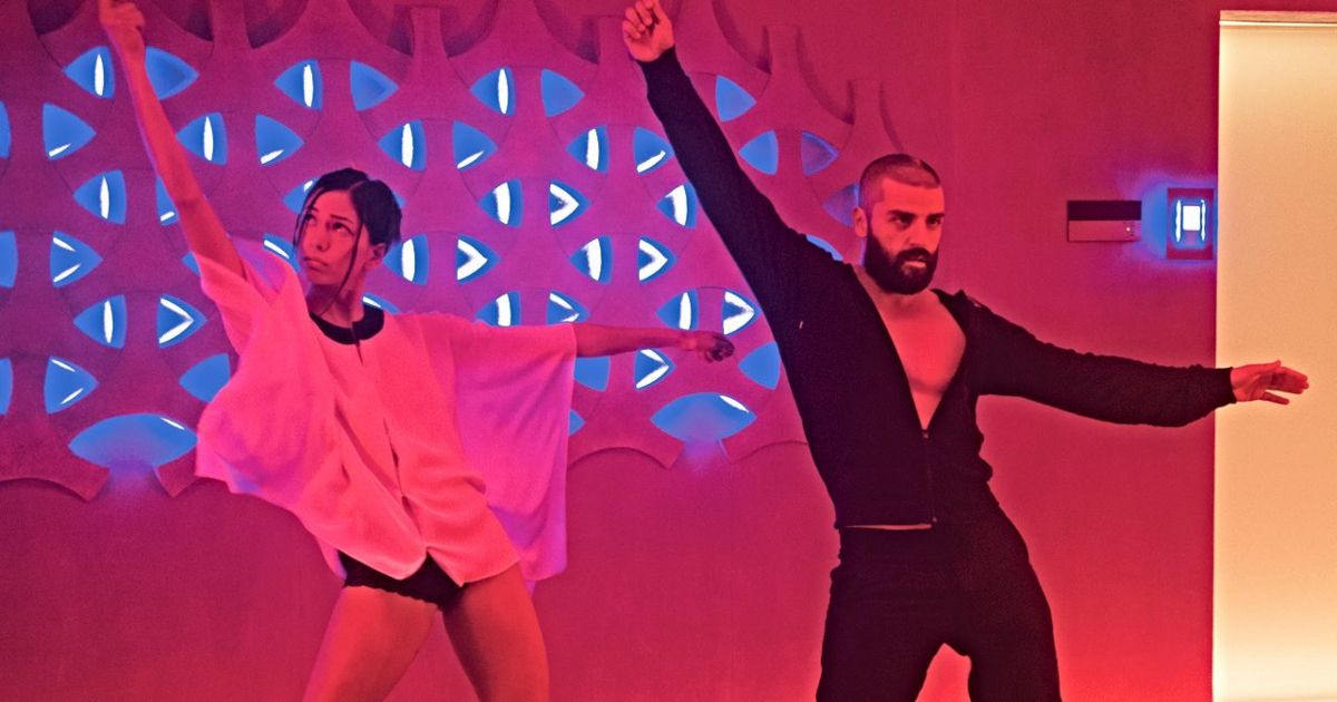 Oscar Isaac and his robot disco dance in the red lit room of Ex Machina