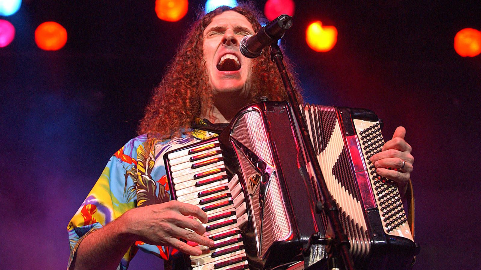Weird Al Yankovic singing into the mic with an accordion