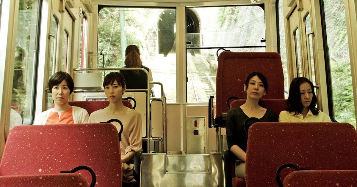 Four women sit in bus seats.