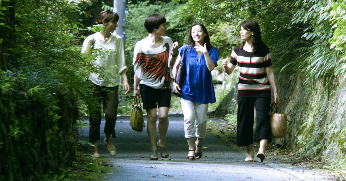 The women of Happy Hour walk through a park