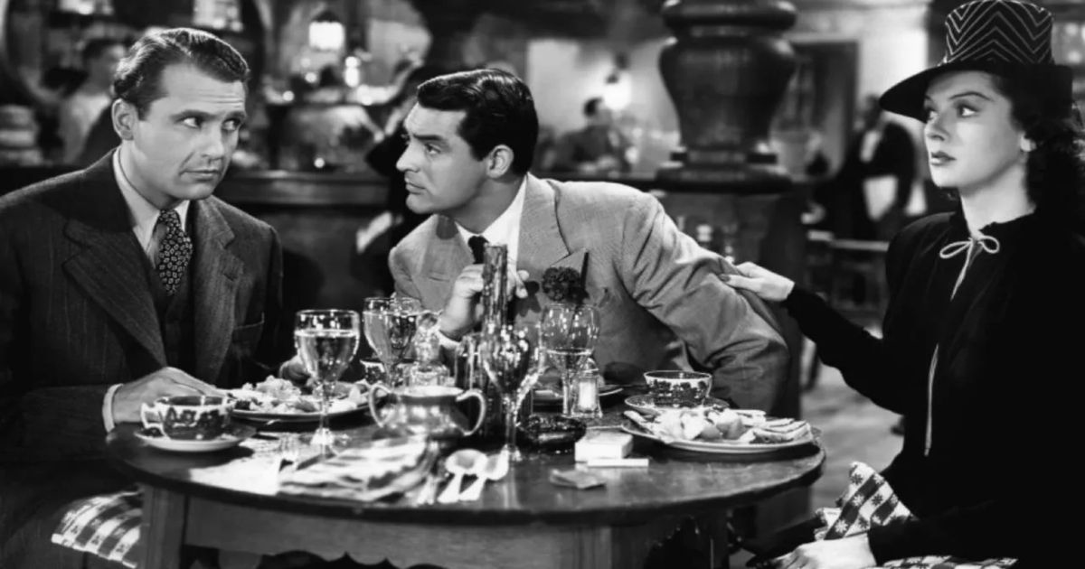 Cary Grant at a restaurant table between a man and a woman in His Girl Friday