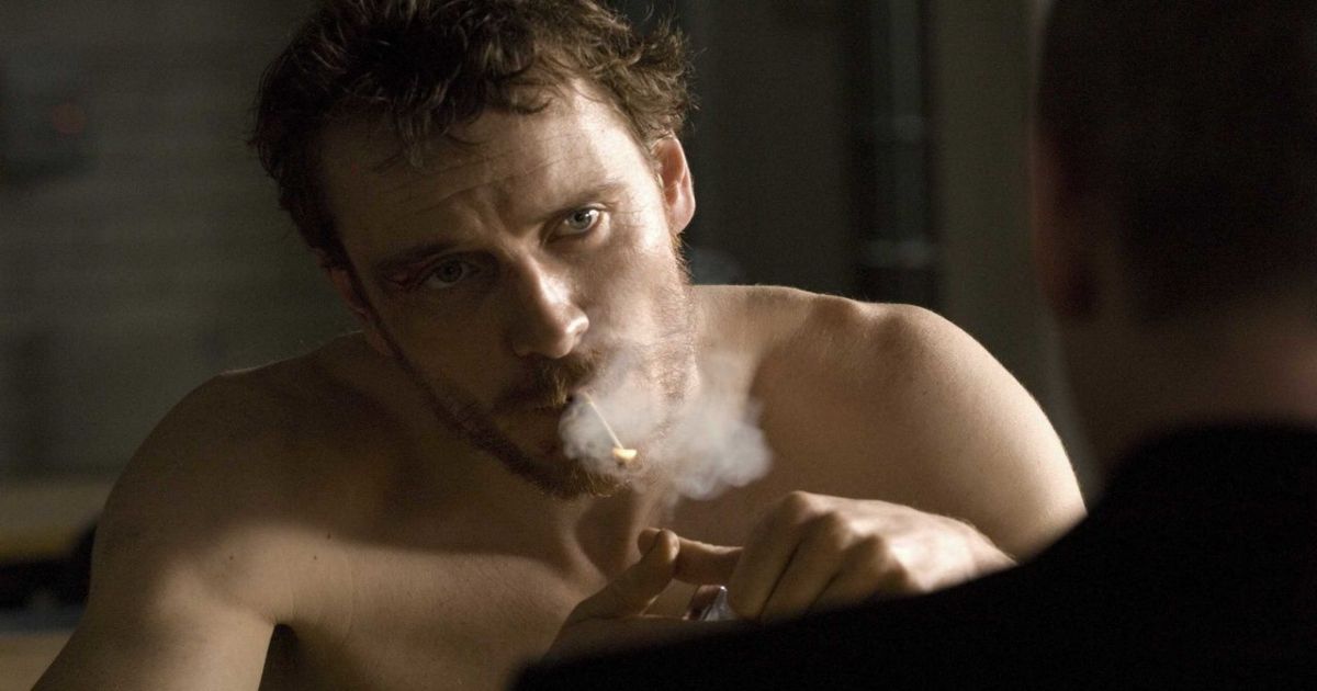 A shirtless Fassbender lights a cigarette in Hunger