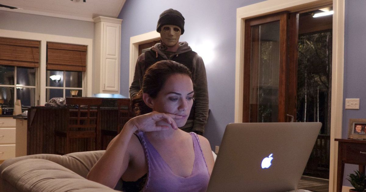 A woman on her couch doesn't notice the masked man behind her in Hush