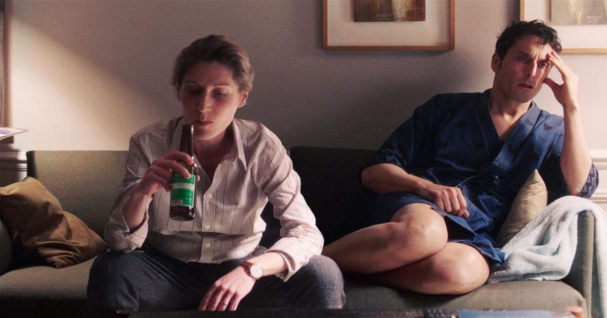 A woman drinks a beer and a man recoils on a couch in I Am Not An Easy Man