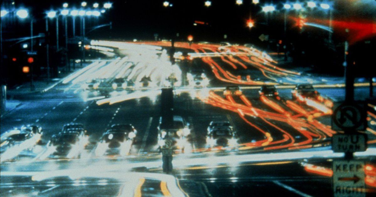 A sped up image of cars driving in the street making trails of light in Koyaanisqatsi