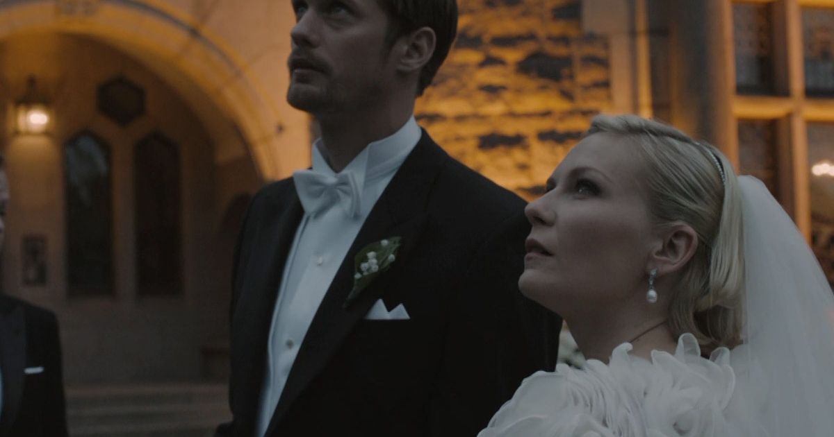 The married couple in tux and gown look up in Melancholia