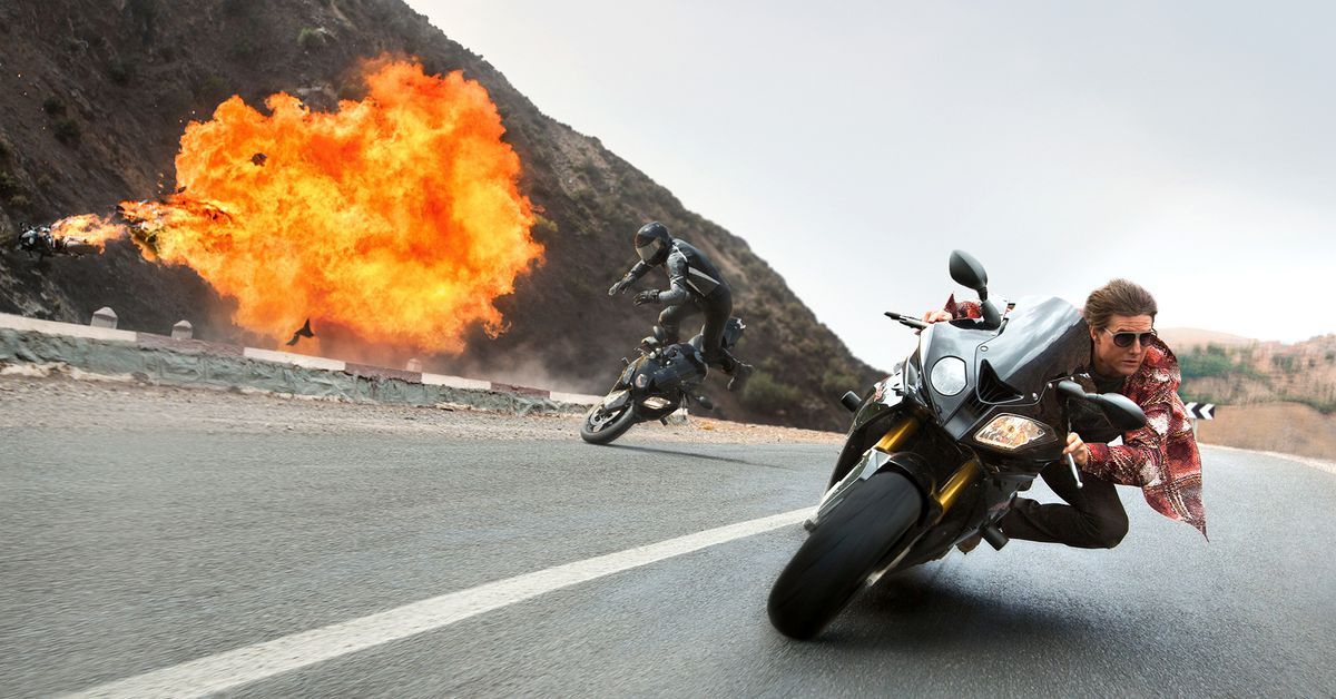 Tom Cruise on a motorcycle chase with explosions behind him in Mission Impossible