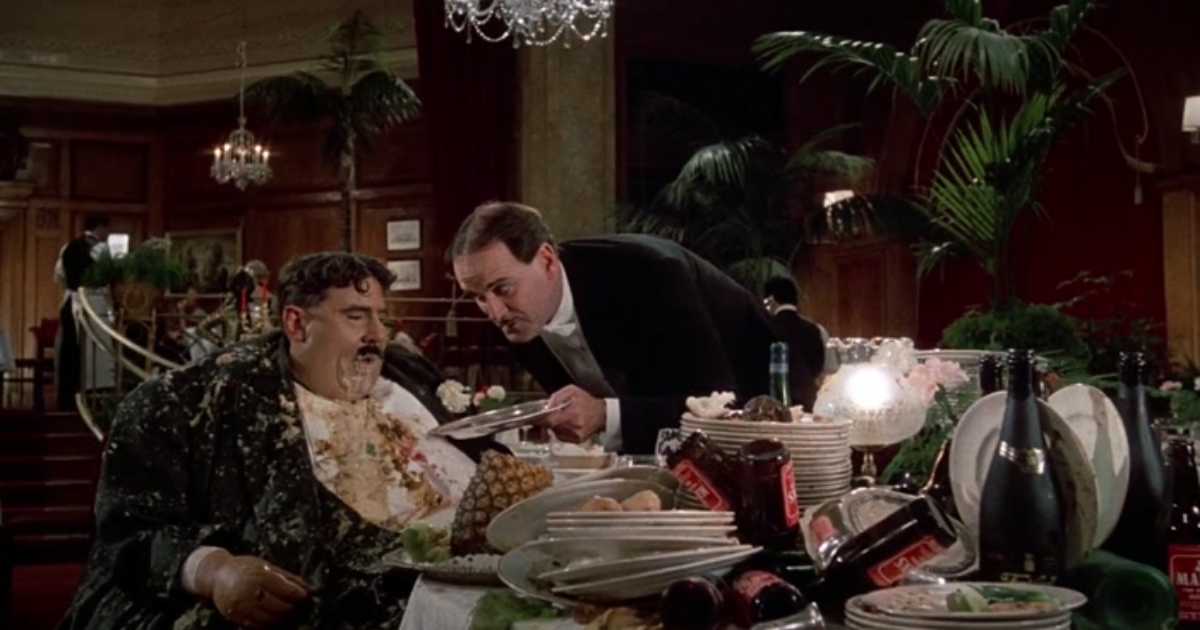 John Cleese serve um homem obeso em um restaurante em O Sentido da Vida de Monty Python