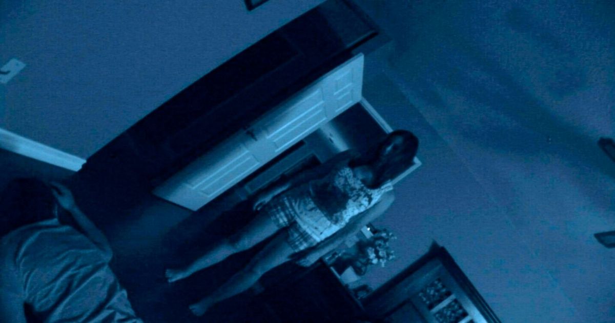 A tilted camera shows Katie standing over a man's body in Paranormal Activity