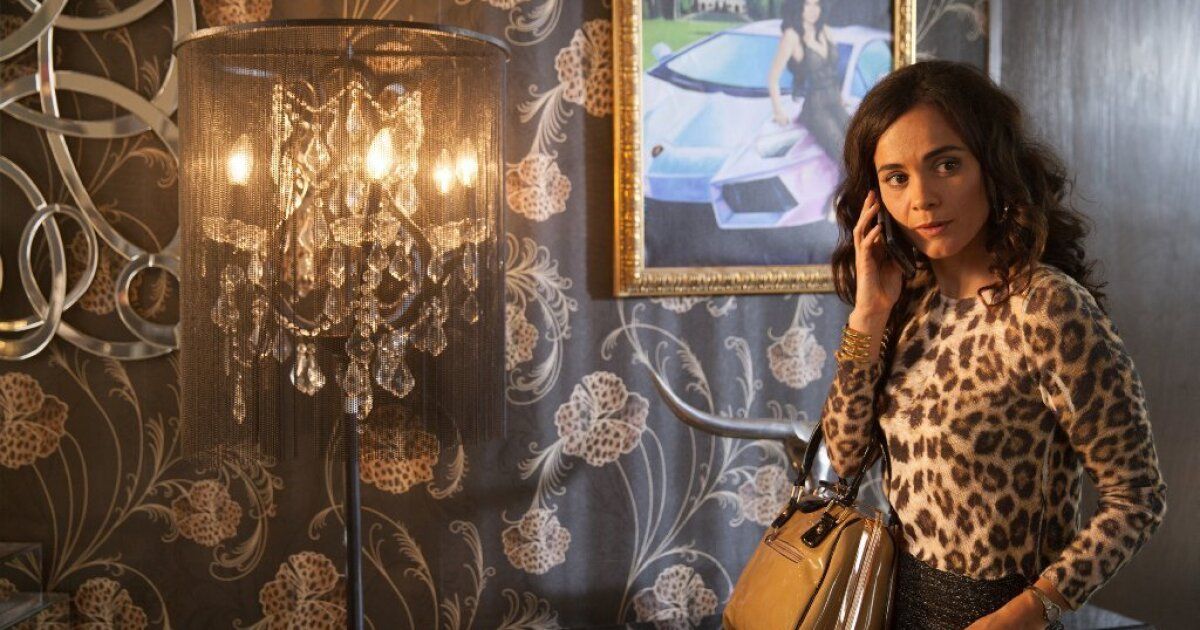 A woman talks on the phone in an ornate dining room in Queen of the South