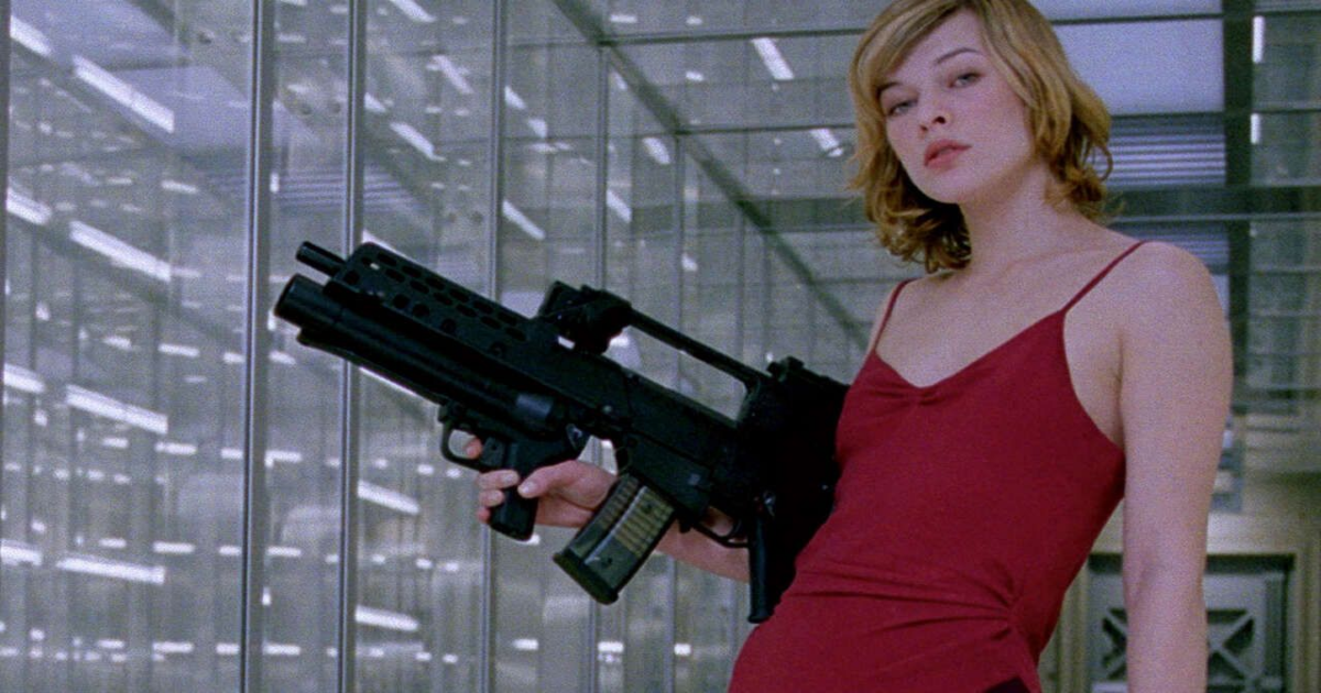 Milla Jovovich in a red dress holds a big gun in Resident Evil