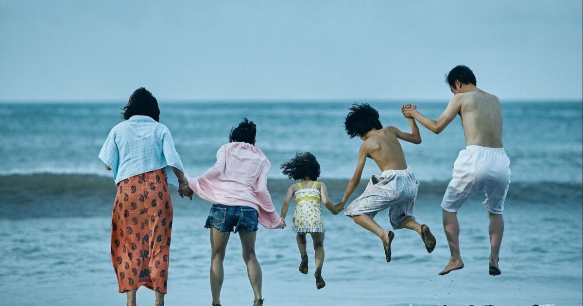 Family jumps into ocean holding hands.
