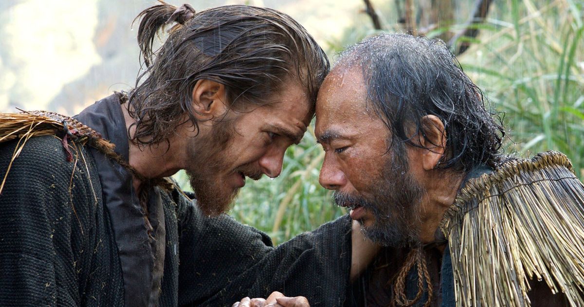 Father Rodrigues (Andrew Garfield) clutches a Japanese man's hand in the rain in Silence