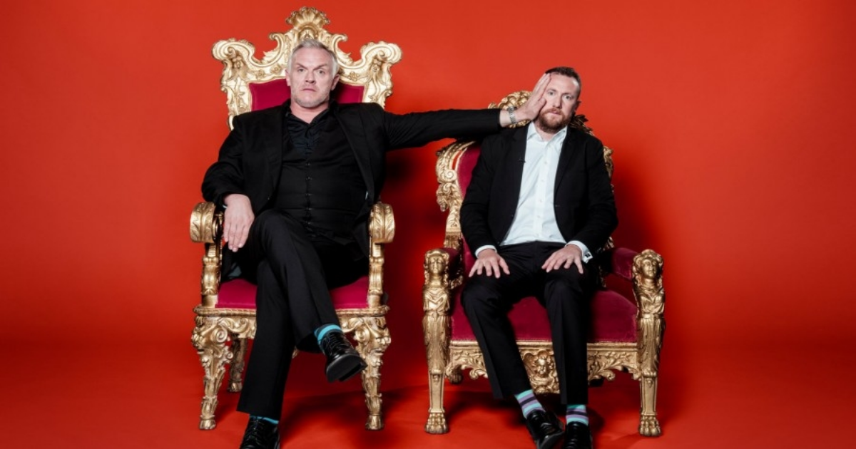 A man pushes another man's head as both sit in royal chairs in Taskmaster