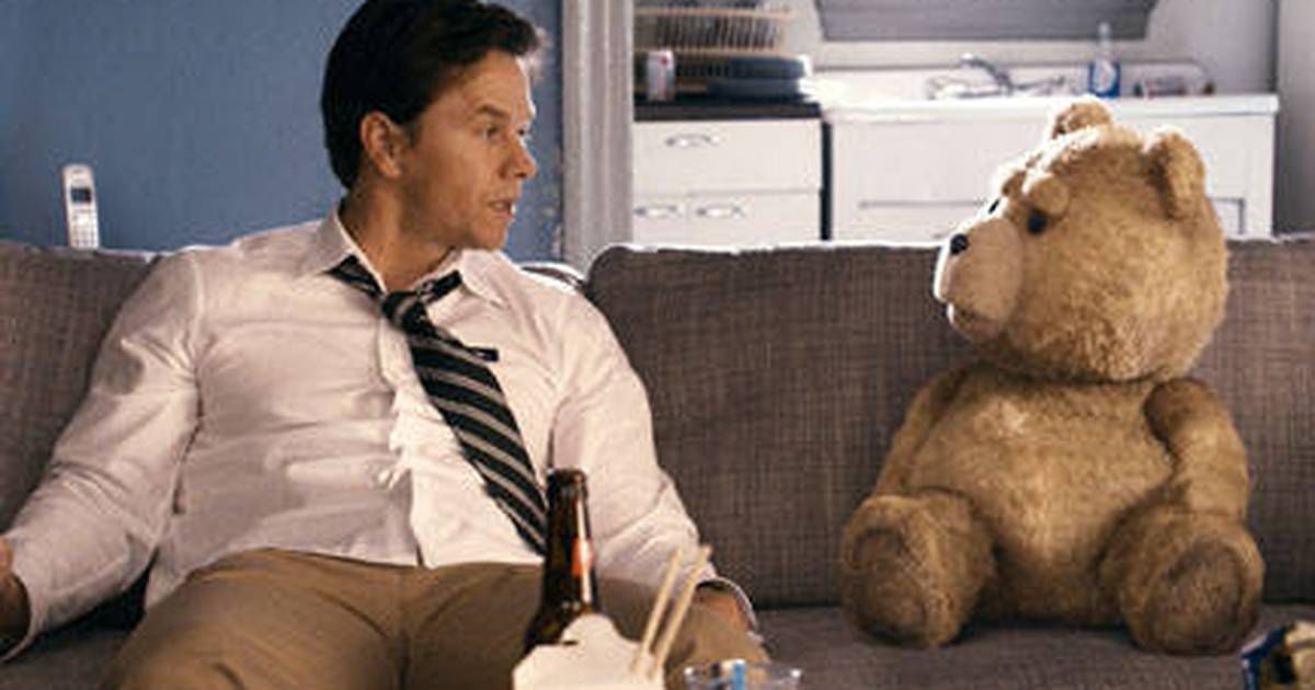 Ted el oso se sienta en el sofá con Mark Wahlberg