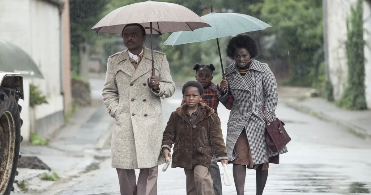 The Congolese family walks holding umbrellas in the street in The African Doctor