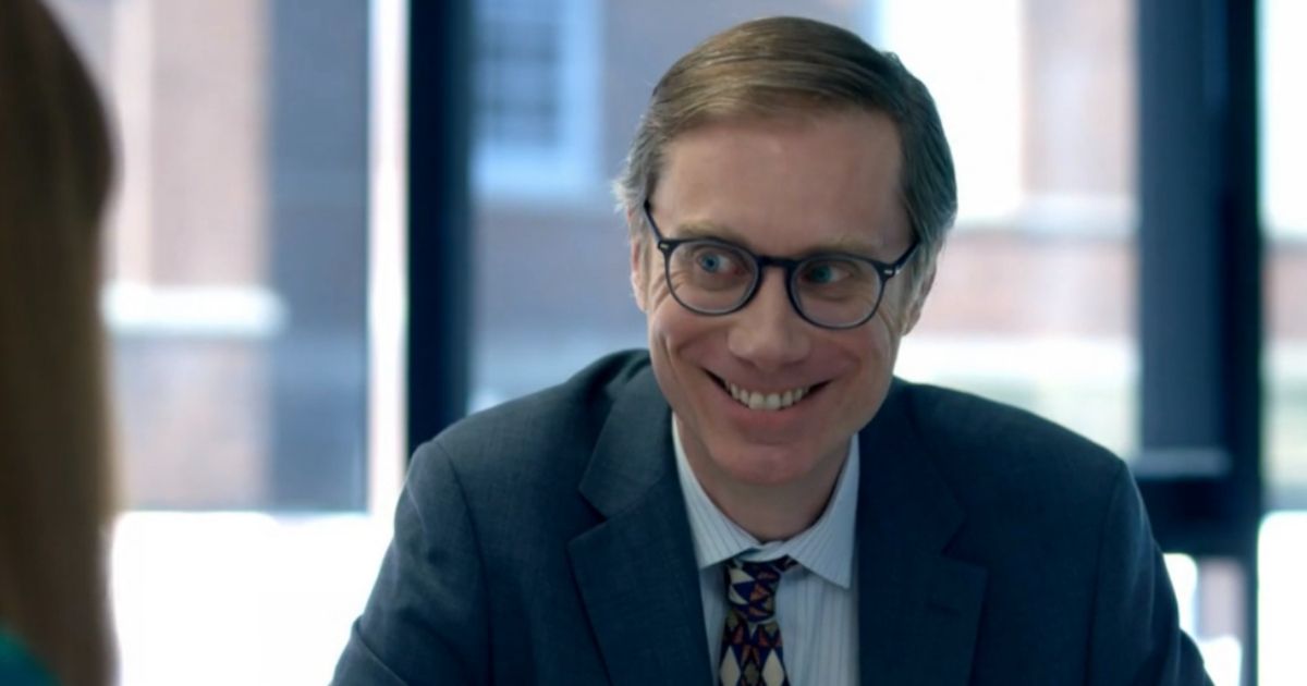 Stephen Merchant smiles in a suit in The Outlaws 