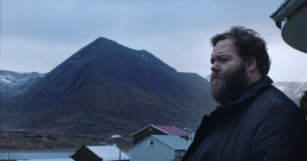 A bearded detective stands with mountains in the background in Trapped