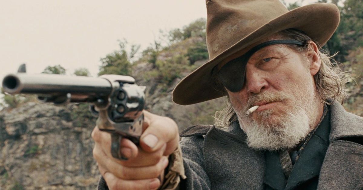 Le maréchal américain Rooster Cogburn ( Jeff Bridges ) arborant un cache-œil, un chapeau de cow-boy et une cigarette, brandissant un revolver dans True Grit .