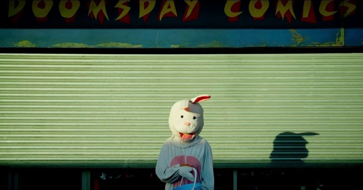 A person with a bunny head in front of a comic store in Utopia