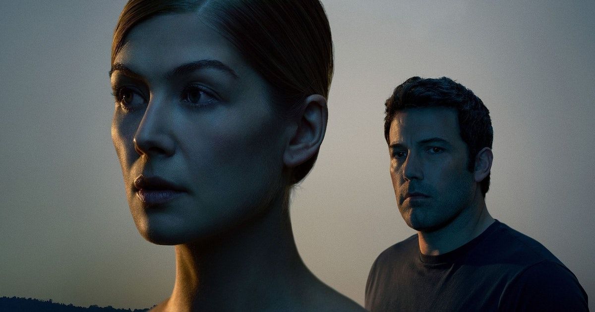 Side of Pike's face is seen as Ben Affleck stands behind her in dark lighting in Gone Girl