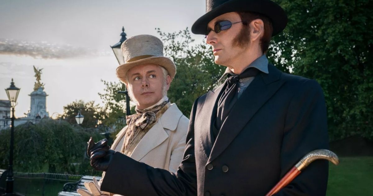 Aziraphale and Crowley standing side by side, dressed in full suits complete with top hats.
