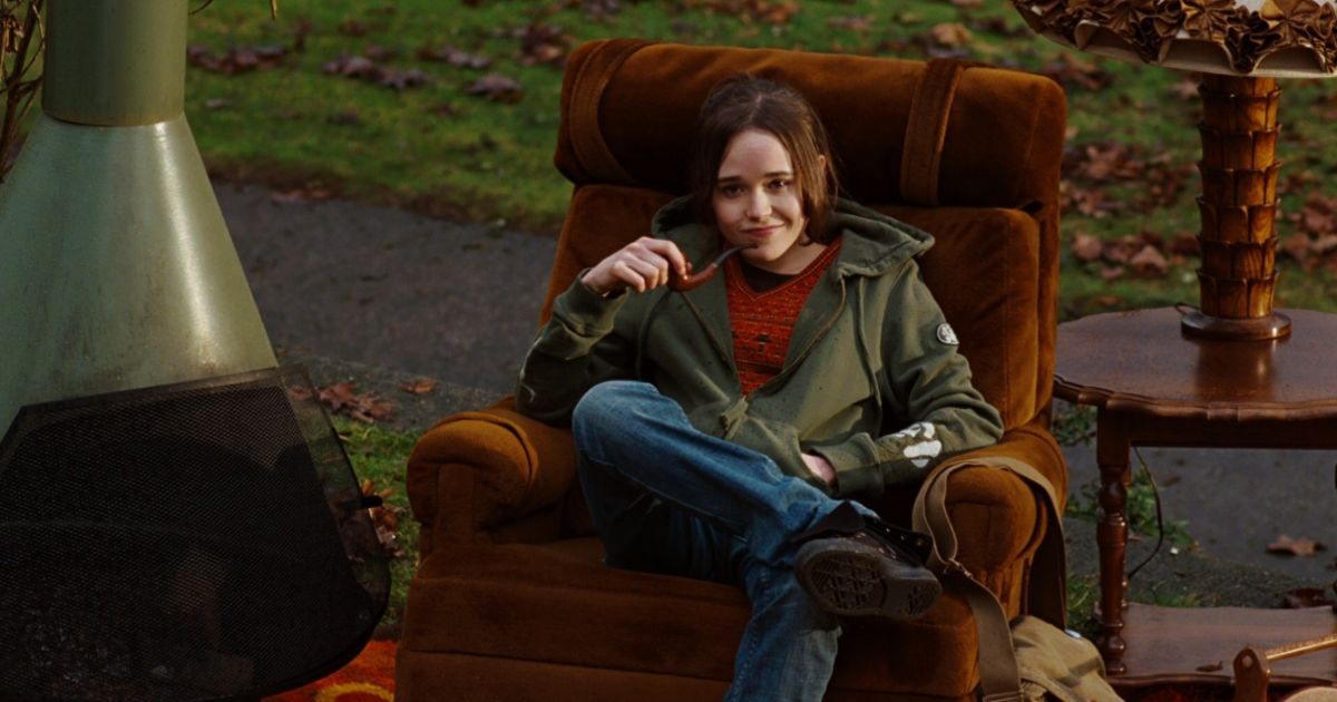 Juno sitting in an armchair on a lawn, holding a pipe in Juno.