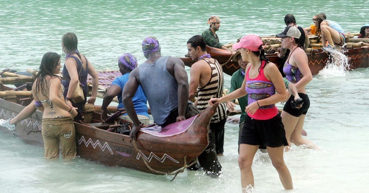Several contestants of Survivor Micronesia exiting boats and pulling it to shore.