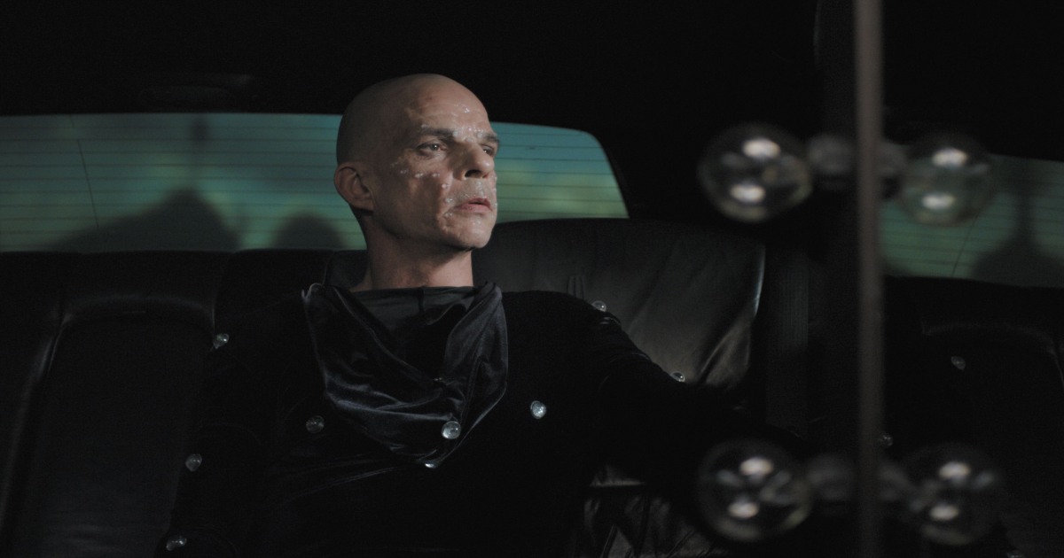 A man in a limousine with motion capture equipment in Holy Motors