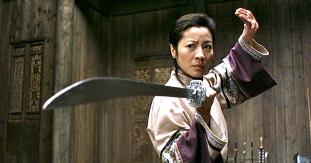 Michelle Yeoh as Yu Shu Lien holds a sword and palm out.
