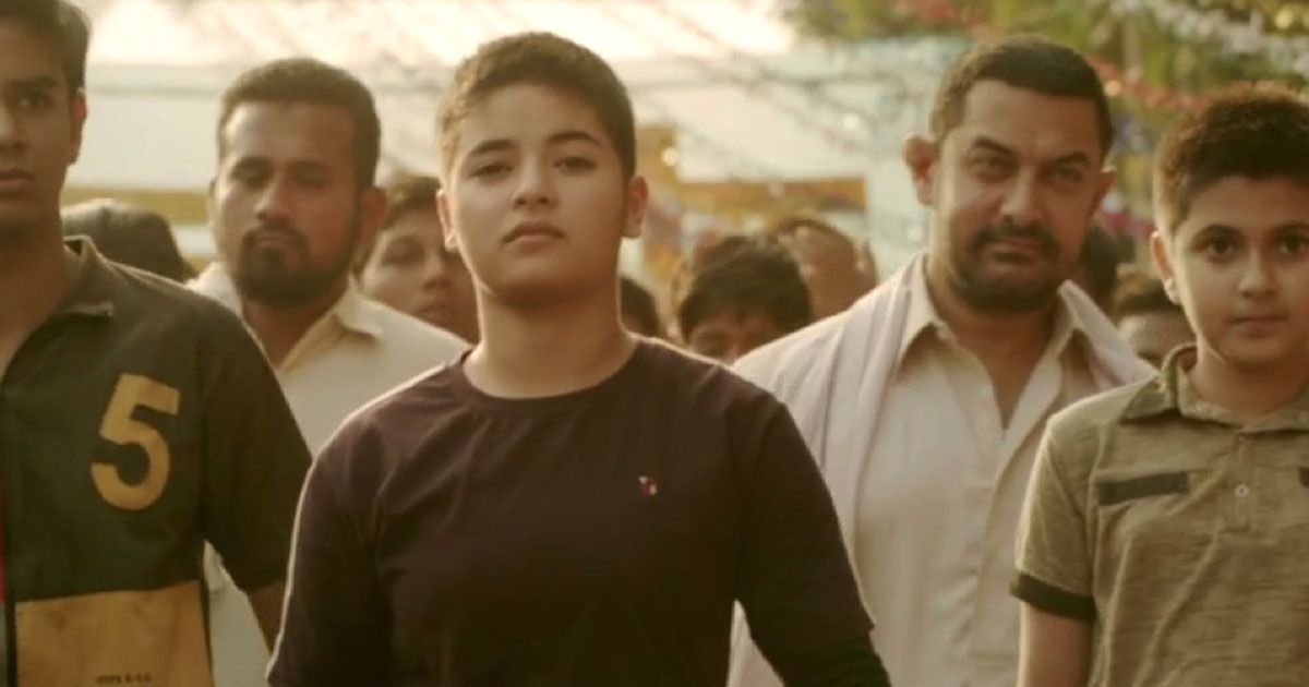Girl with buzzcut stands around men in the movie Dangal