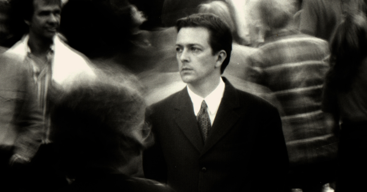 Man in a suit in a crowd of people in the Christopher Nolan film Following