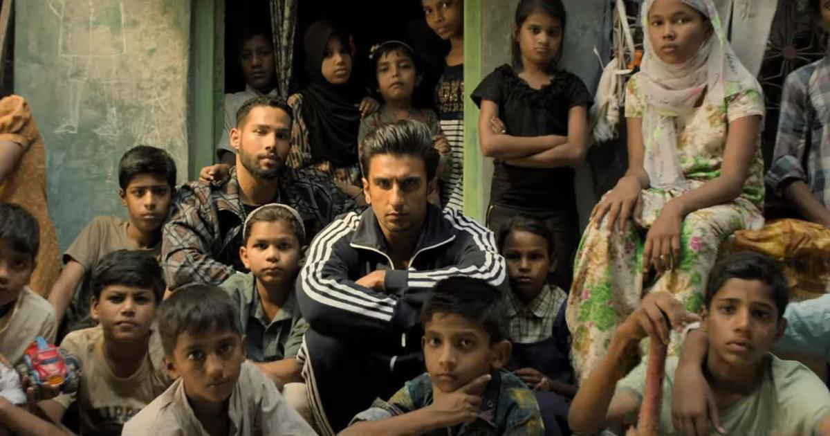 Jovem adulto sentado com um grupo de meninos e duas meninas nas favelas de Mumbai.