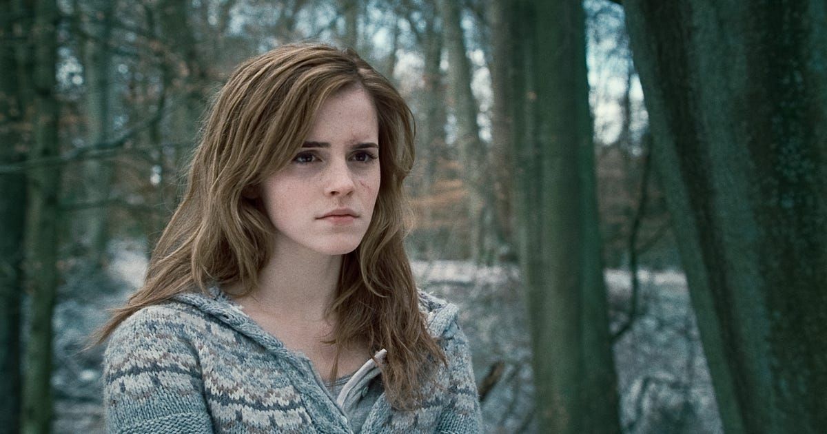 Girl stands in snowy woods looking solemn.