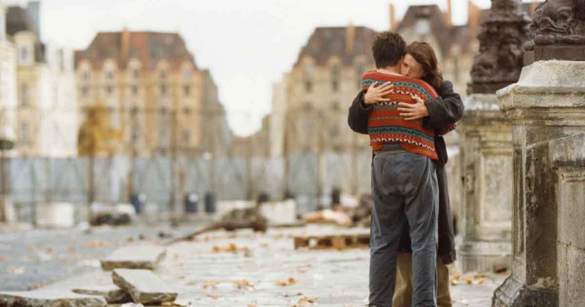 Two people hug on a bridge.