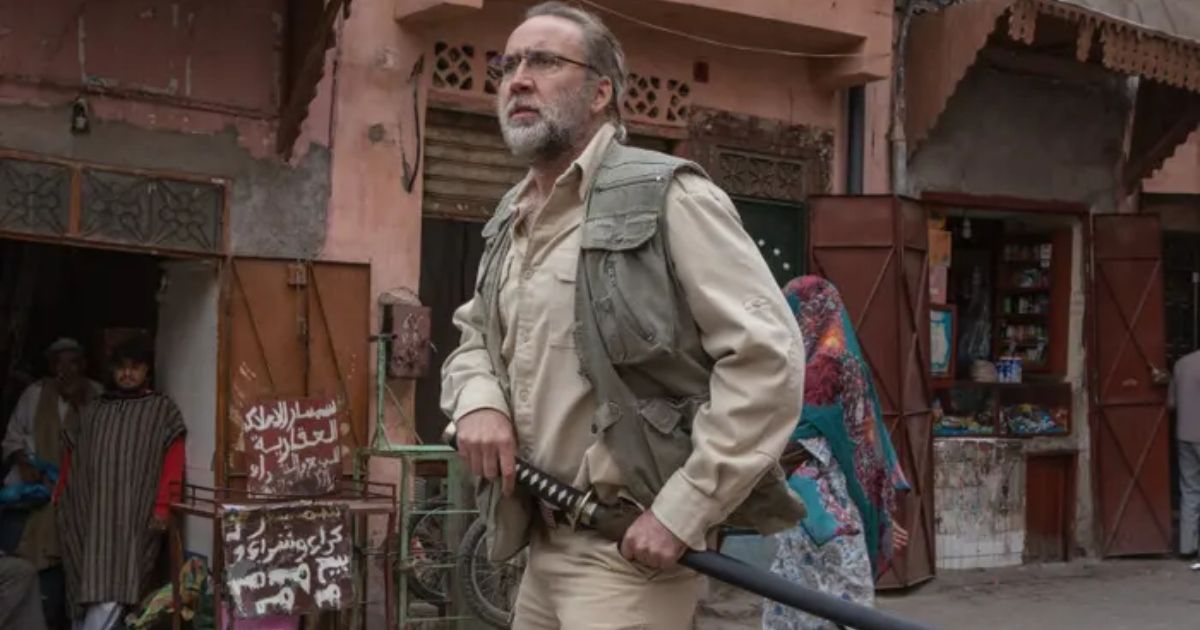 Nicolas Cage in Army of One, gripping a sword as he walks down a street