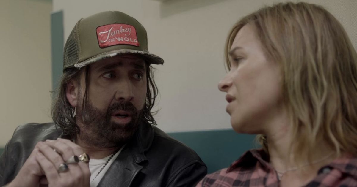 Nicolas Cage in Between Worlds with a full beard, long hair, and a baseball cap