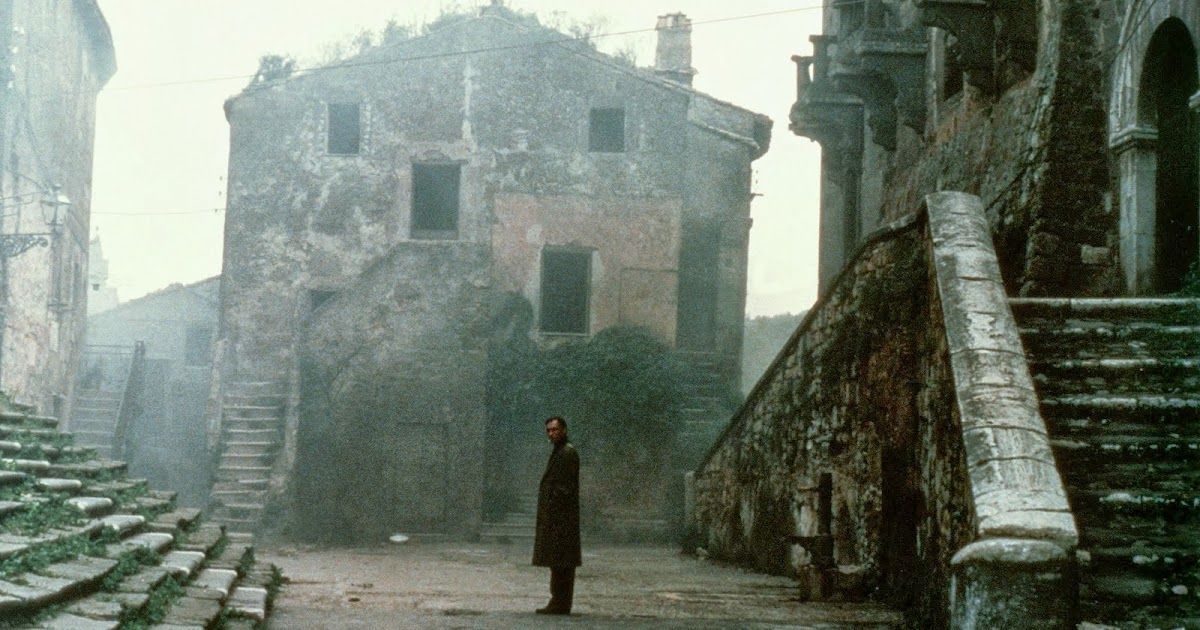 Man stands in front of ruined city.