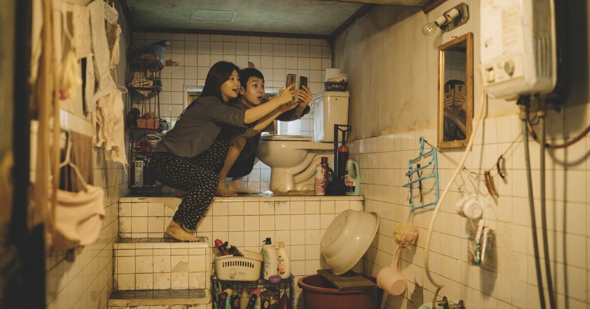 Un garçon et une fille tiennent des téléphones portables au-dessus des toilettes.