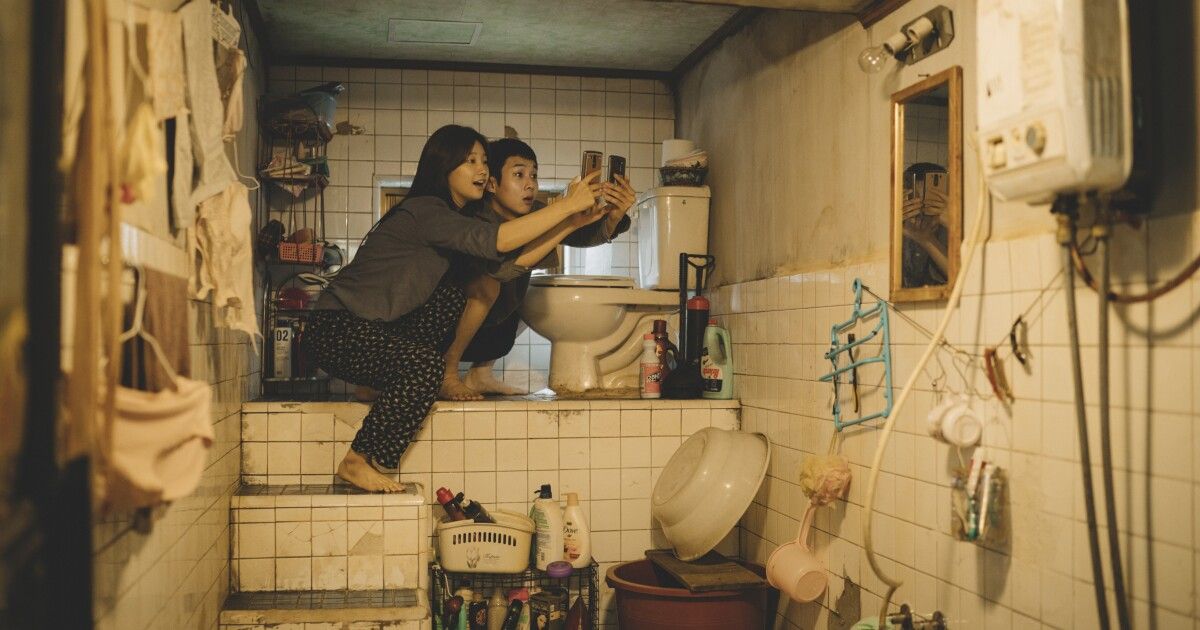 Boy and girl hold up cellphones over toilet.