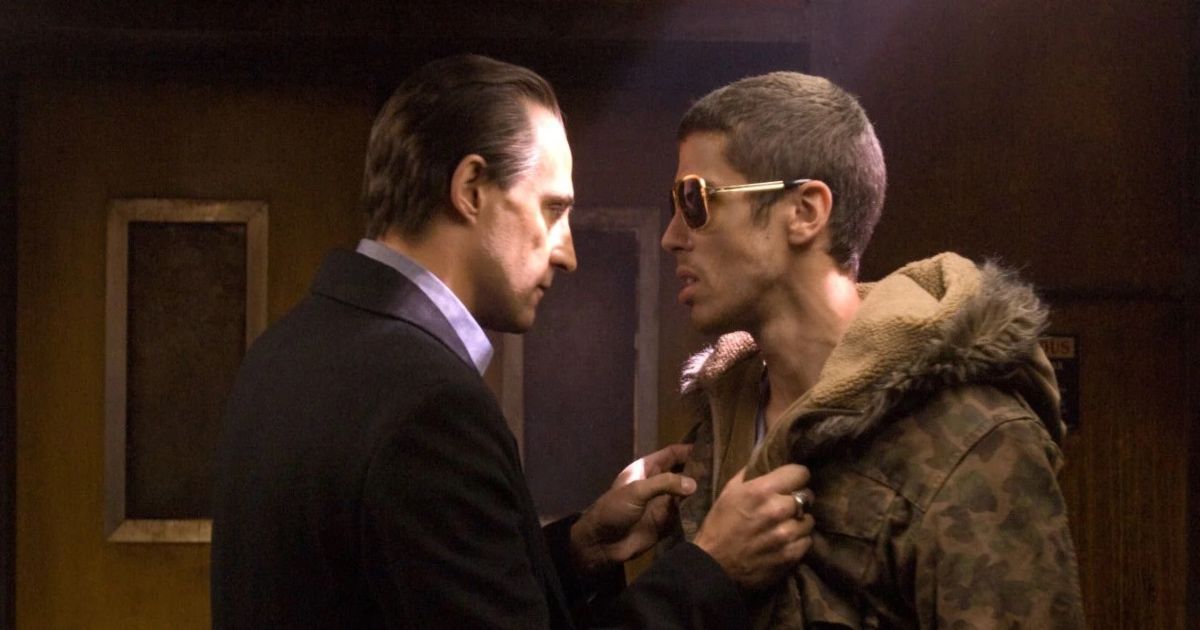 Man in suit grabs another man's fur jacket. They stare each other down in RocknRolla