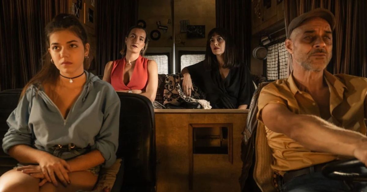 Four people sit in a van; a girl and man in the front, two women in the back.