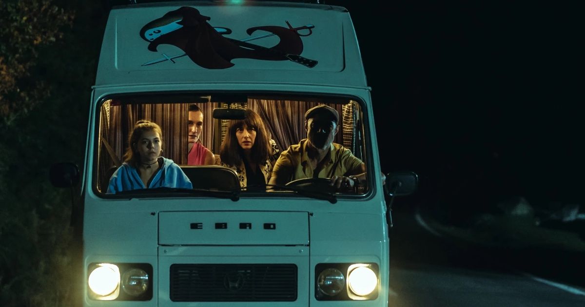 Four people sit in a van; they're driving at night.