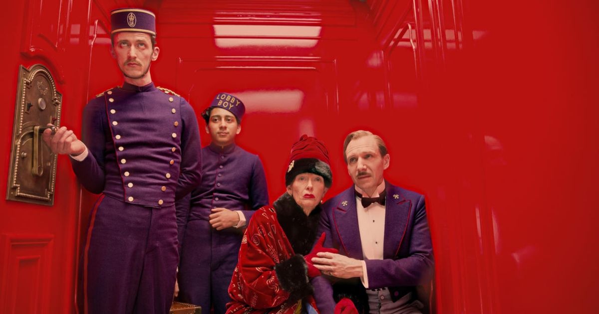 Dentro de un ascensor rojo brillante con algunas personas en el Grand Budapest Hotel
