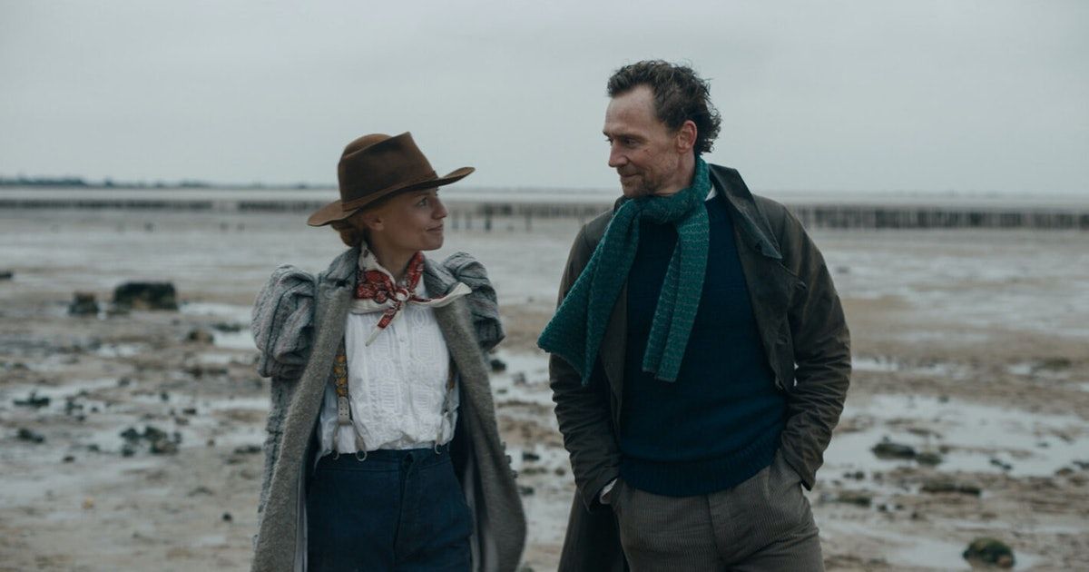 Woman and man walk along marsh.