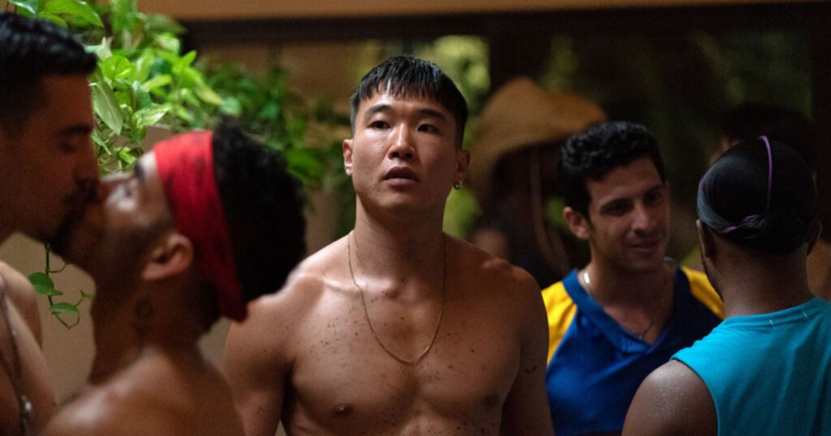 Joel Kim Booster as Noah looking for someone at a party in Fire Island