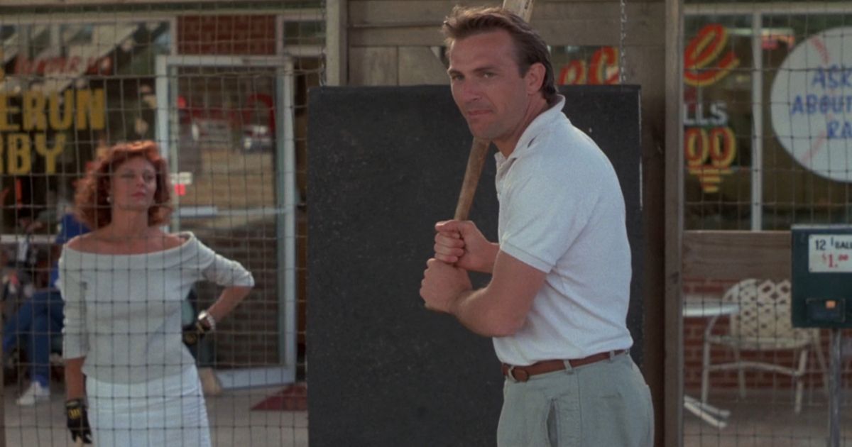 Kevin Costner com um taco de beisebol enquanto Susan Sarandon assiste em Bull Durham