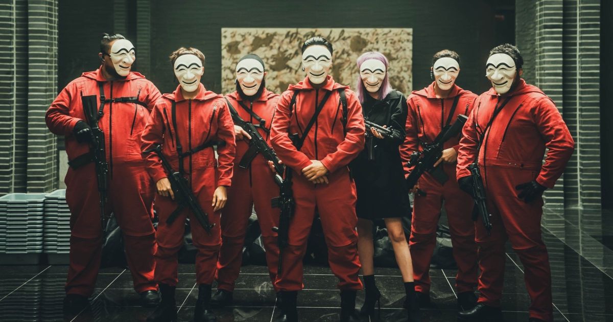 Group of people with guns and red jumpsuits stand in a line.