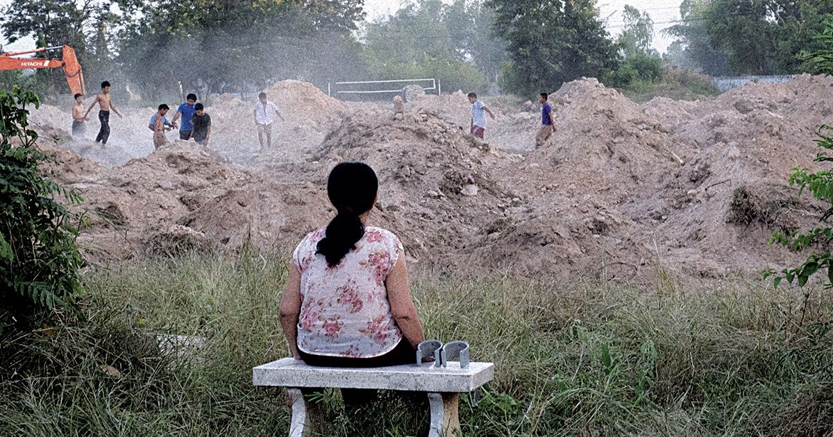 Woman sits in front of construction site.